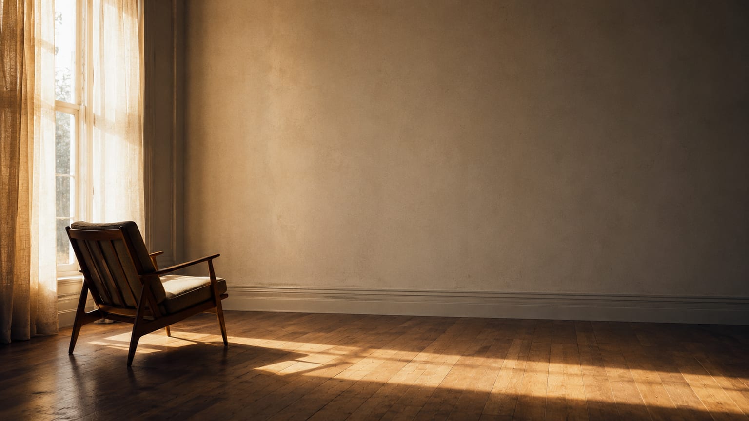 A mid-century chair by a sunlit window in an otherwise empty room.