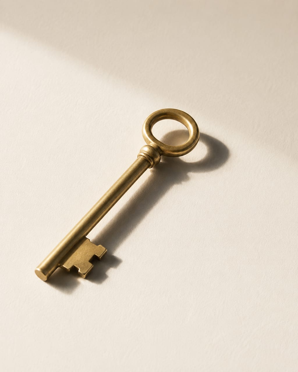 A single brass key on a cream surface.